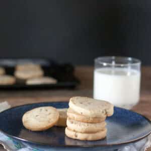 Stack of pecan sandies on blue plate with glass of milk.