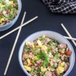 Two bowls of pork fried rice with blue bowls.