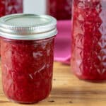 Jars of raspberry jam on barnwood board.