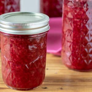 Jars of raspberry jam on barnwood board.