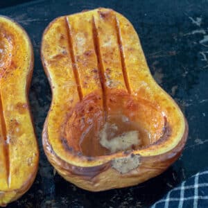 Half of a roasted butternut squash on antique tray.