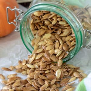 Roasted pumpkin seeds spilling out of canning jar.