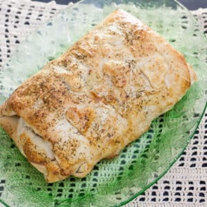 Salmon wrapped in pastry on green platter.