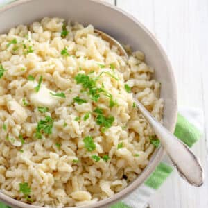 Beige bowl filled with Spaetzle and garnished with fresh parsley.