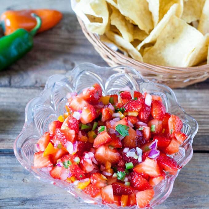 Strawberry salsa in glass serving dish with tortilla chips.