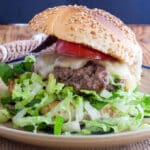 venison cheeseburger on a Kaiser rolls with lettuce and tomato slice.