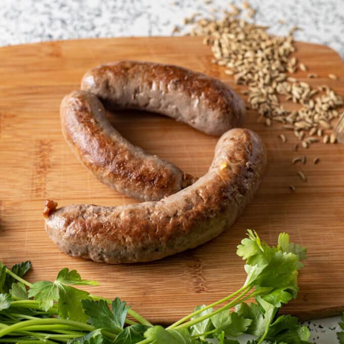 3 Italian sausage on wooden cutting board.