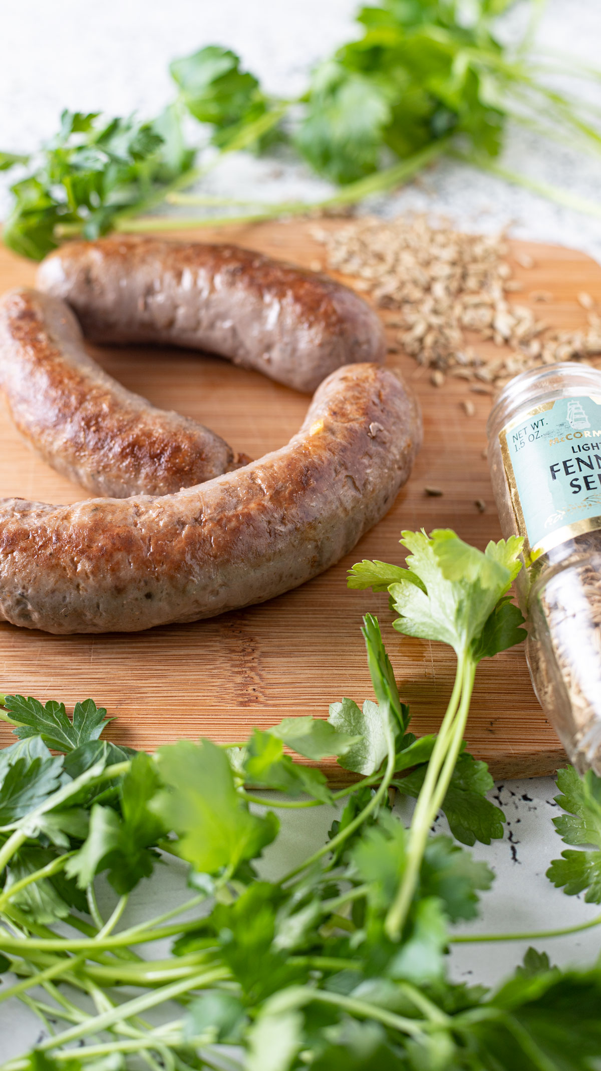 Three venison Italian sausage on wooden board with fennel.