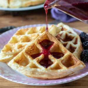 Close up of syrup pouring on waffles.