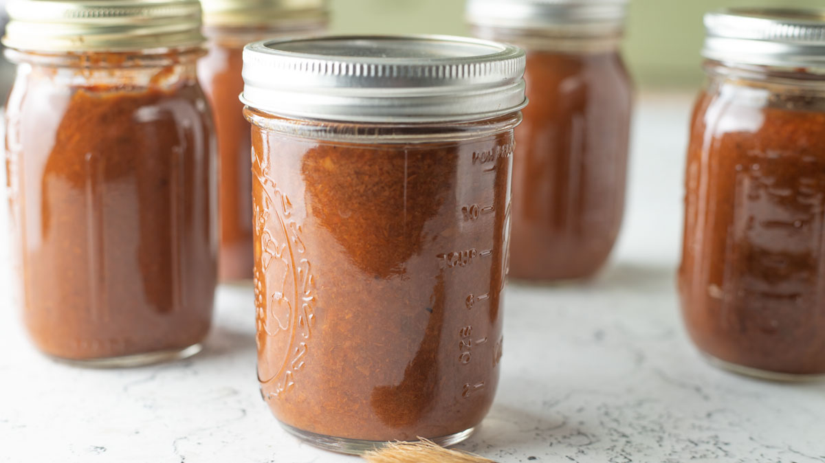 Jars of apricot sauce on white board.