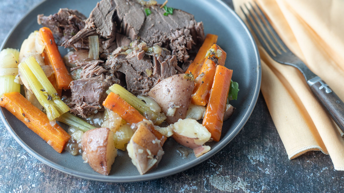Venison Roast sliced on plate with vegetables.