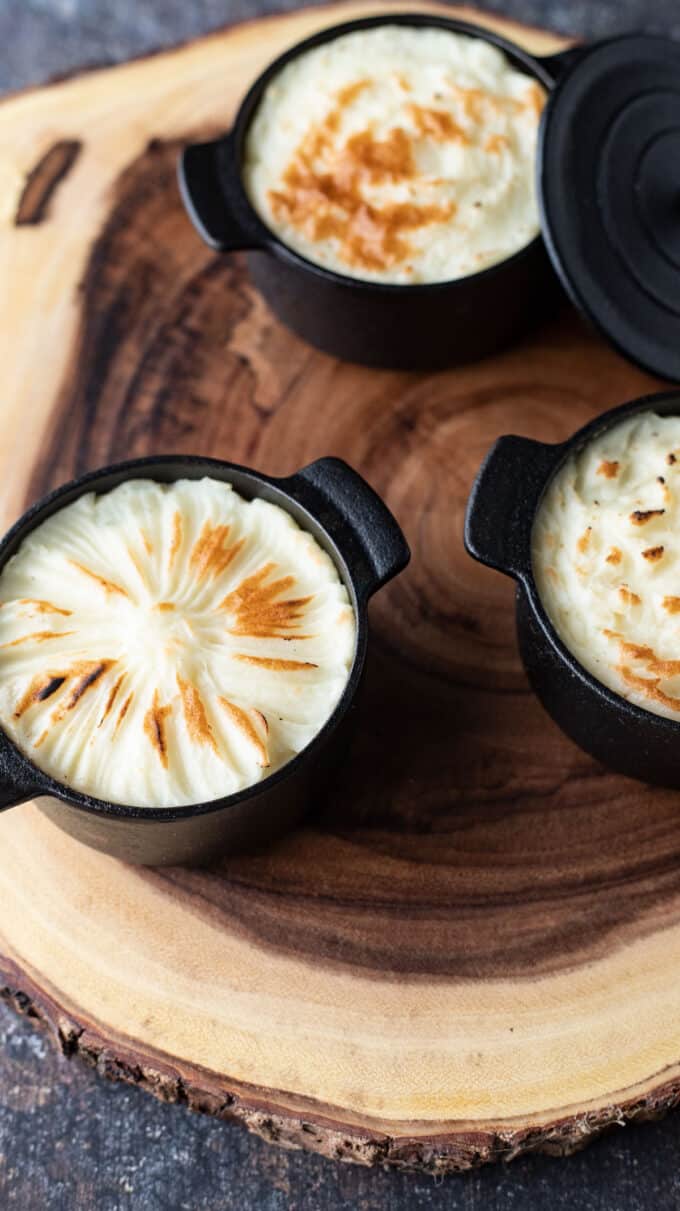 Three mini cast iron ramekins with shepherd's pies.