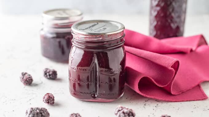 Jars of syrup on white board with pink kitchen towel.