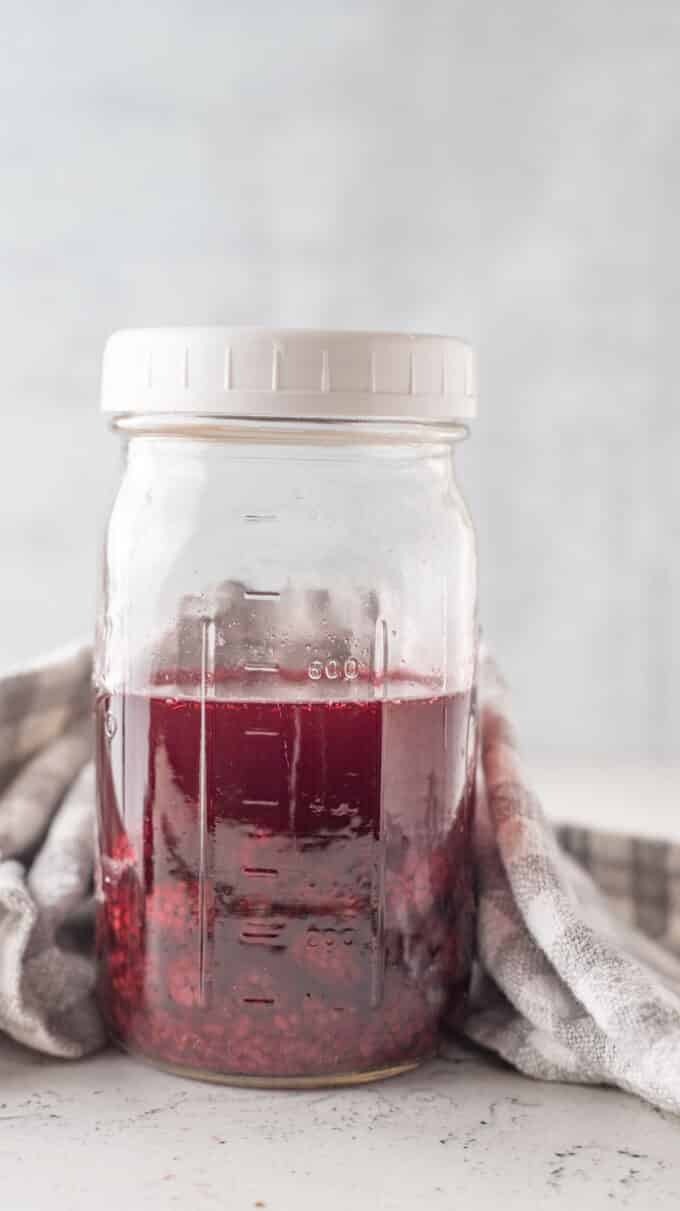 Berries steeping in vinegar in a jar.