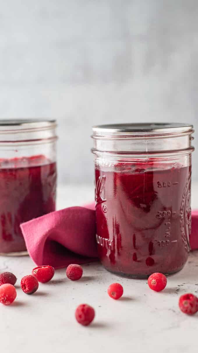 Jars of cranberry sauce with pink kitchen towel.