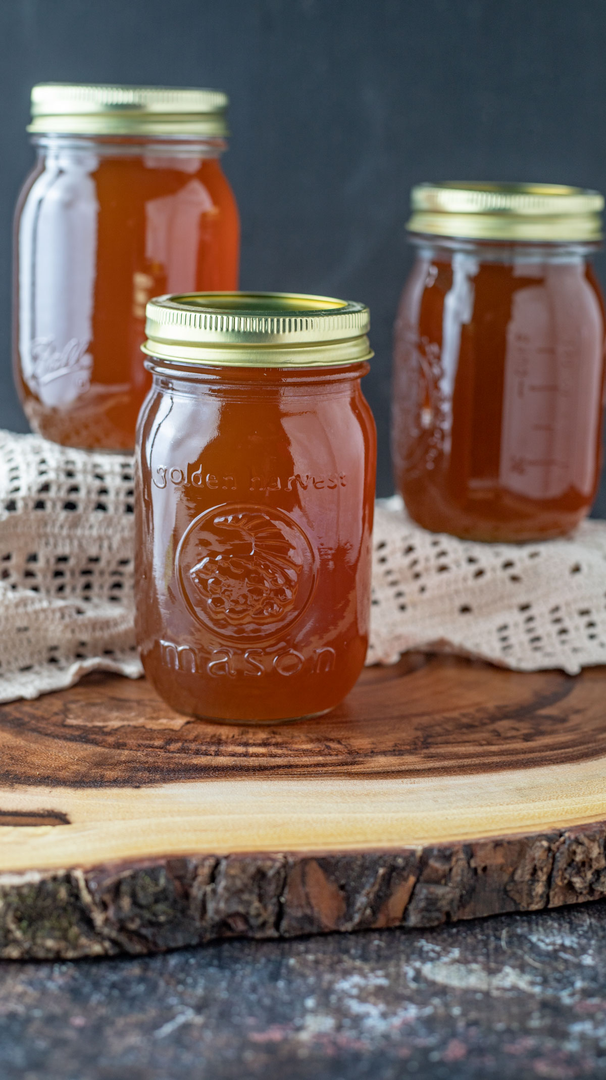 Jars of maple syrup on slab of wood.