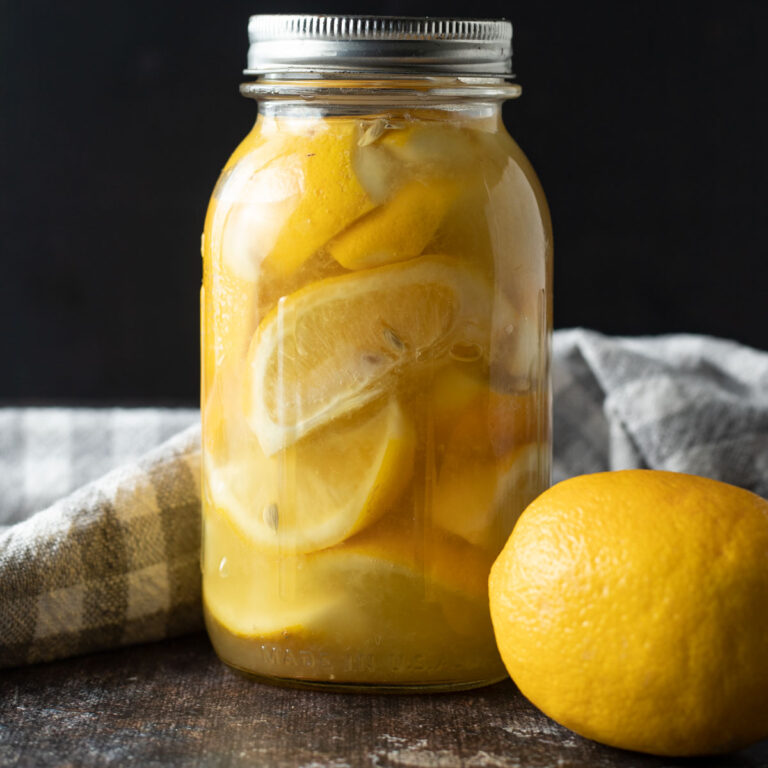 Jar of fermented lemons with a fresh lemon.