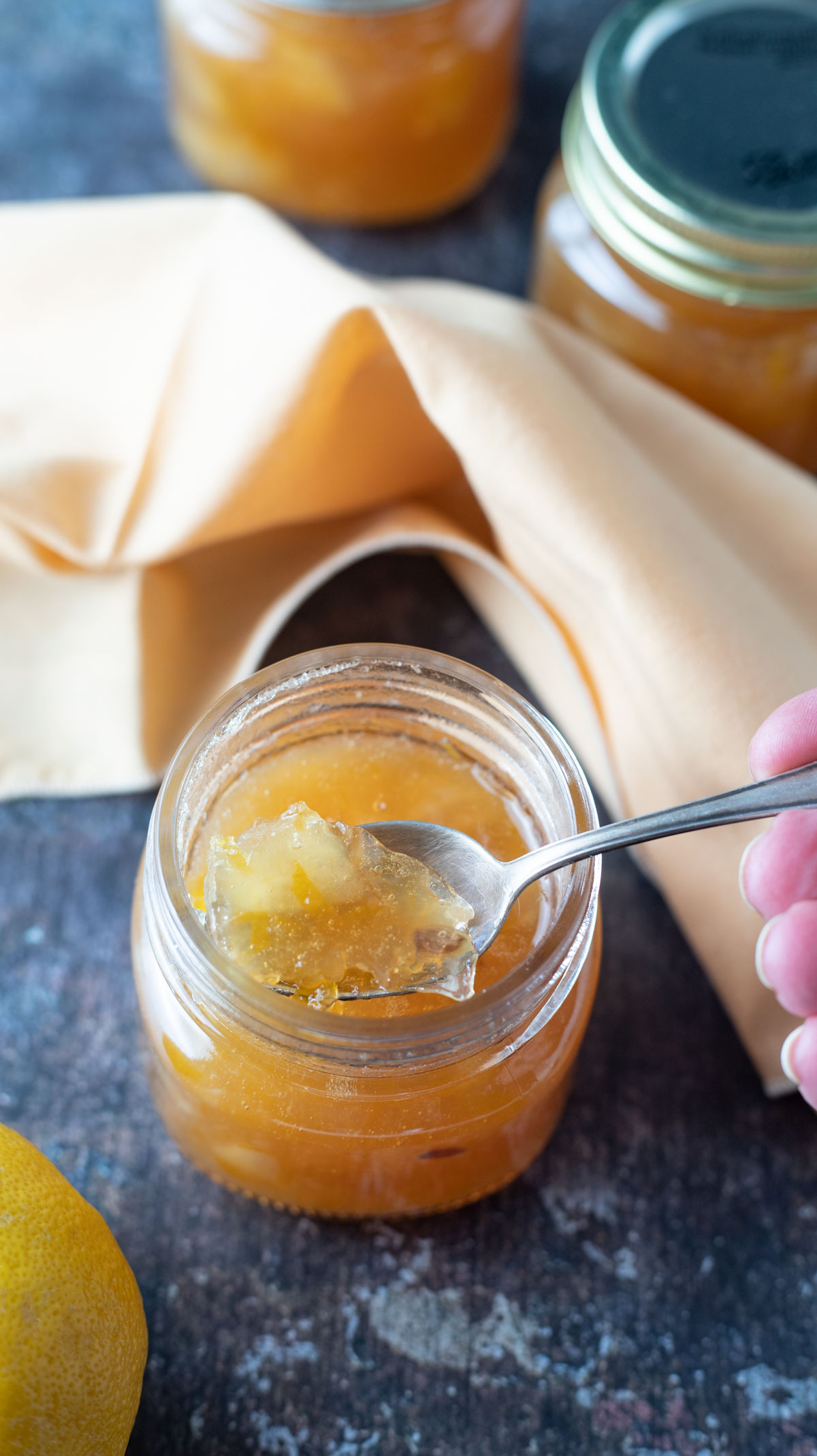 Woman's hand scooping marmalade out jar.