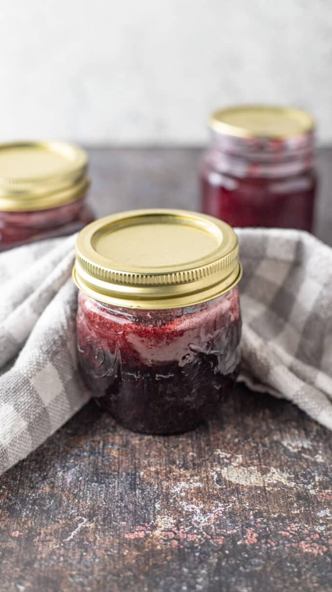 Three jars of syrup on black board.