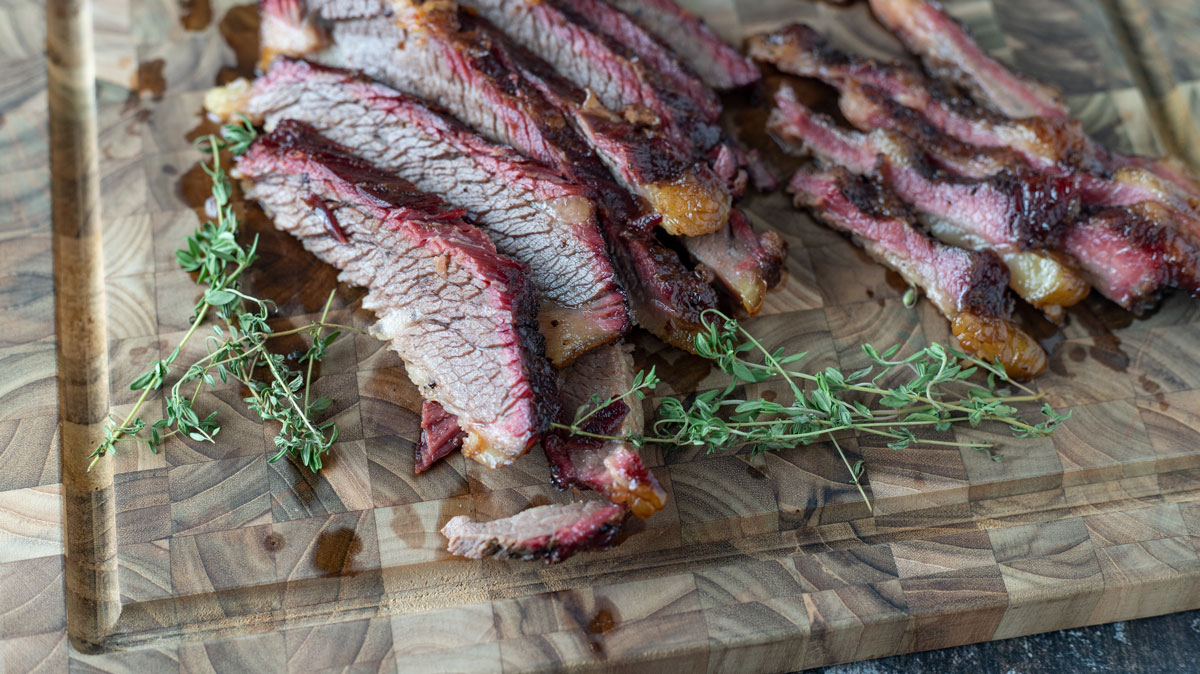 Sliced beef brisket on a laminated wood board.