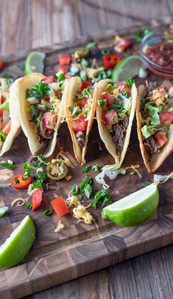 Tacos on wooden cutting board.