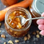 Woman's hand spooning out carrot cake jam from jar.