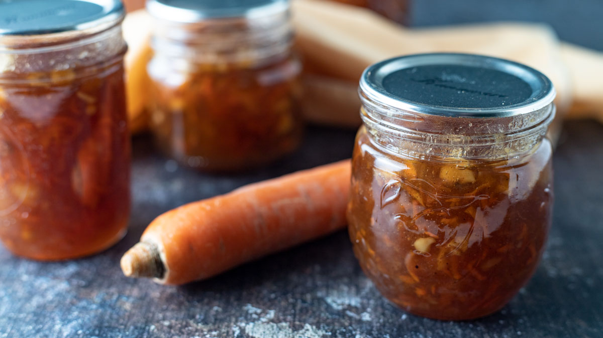Jars of carrot cake jam with a fresh carrot.