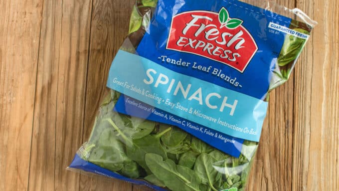 Bag of store bought spinach on barnwood.