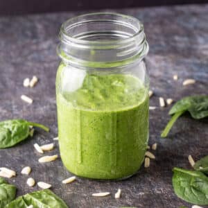 Jar of pesto on black board.