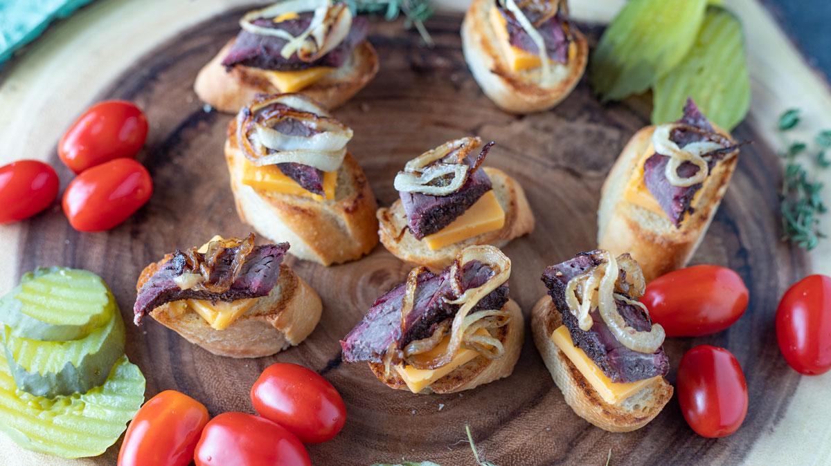 Brisket appetizers on wood plate.