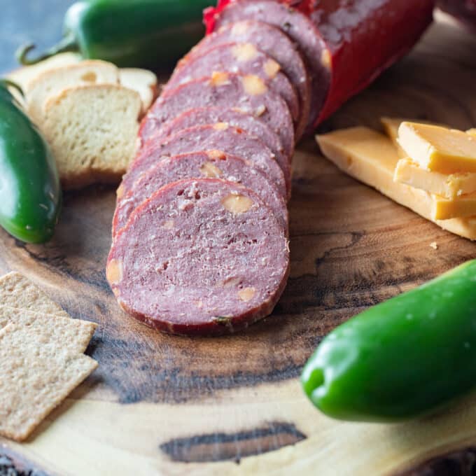 Sliced sausage with cheese in it and crackers.
