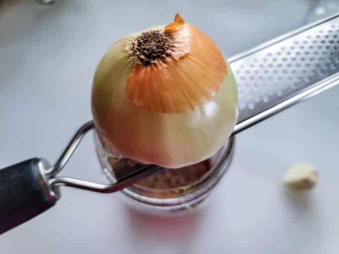 Grating onion over container.