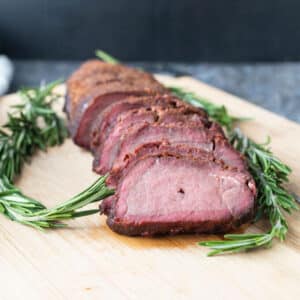 Sliced backstrap on board with fresh rosemary garnish.