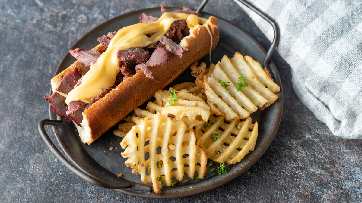 Thin slice venison on hoagie roll with cheese sauce.