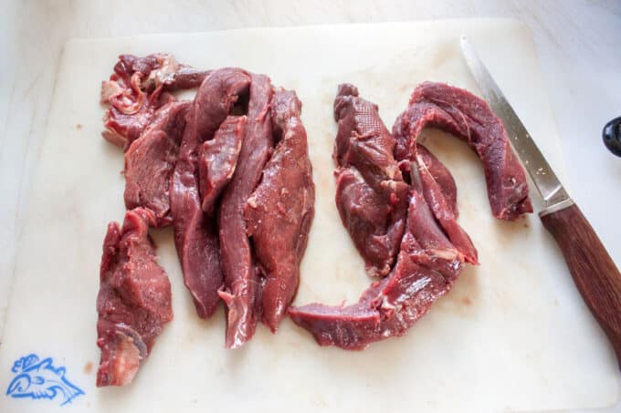 Sliced venison on board ready for grinding.