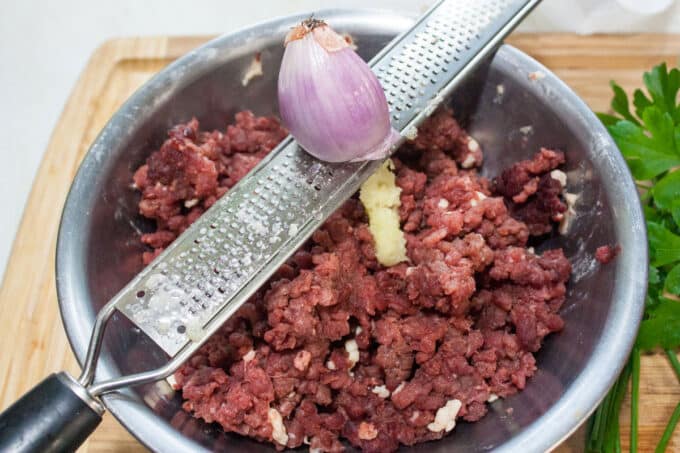 Grating shallot on microplane directly over the ground meat.