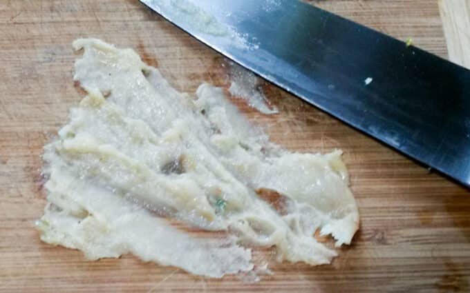 Pasted garlic on board with knife.