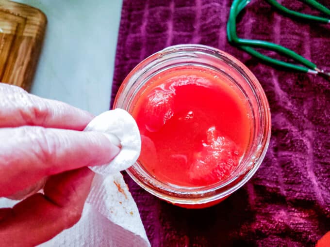 Wiping jar rims with paper towel.