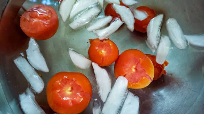 Blanch tomatoes added to ice water bath.