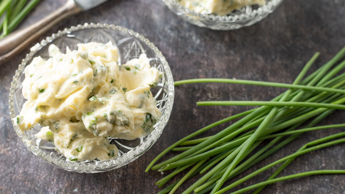 2 small bowl of chive butter on black background.