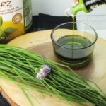 Decanter pouring chive oil in bowl.