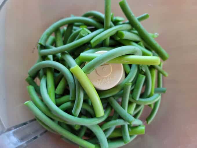 Chopped scapes in food processor bowl.