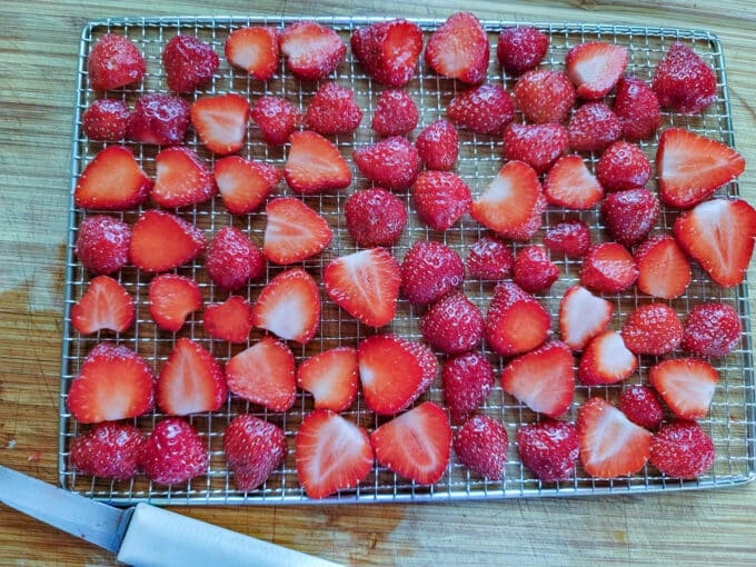 Strawberries sliced lengthwise on dehydrator rack.