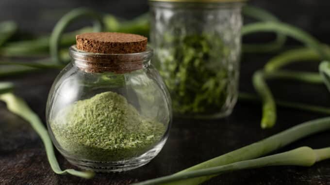 Garlic scape powder in a mini spice jar with cork lid.