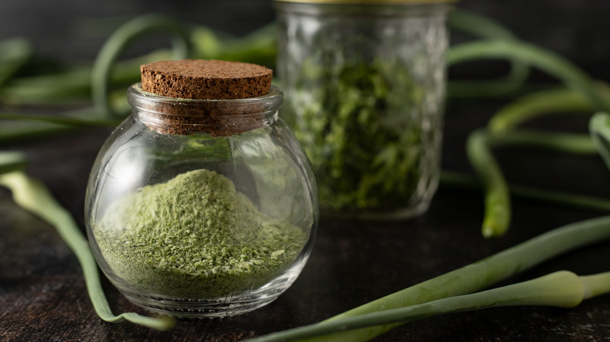 Garlic scape powder in a mini spice jar with cork lid.