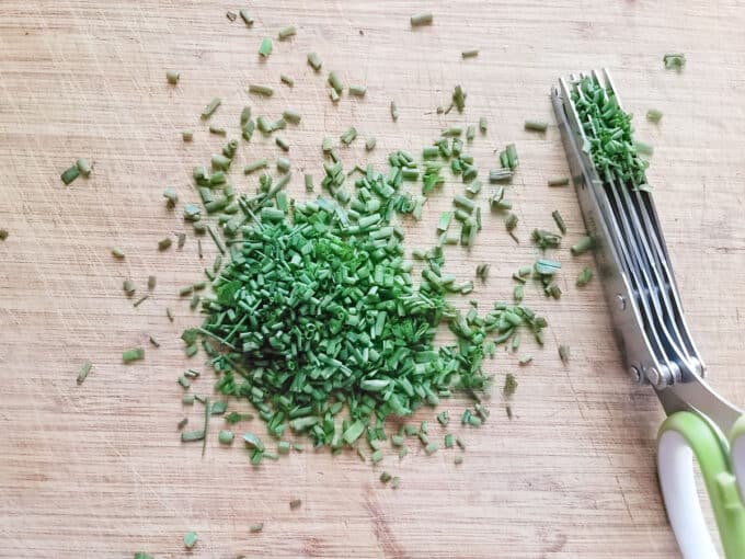 Chopped chives on board with herb shears.