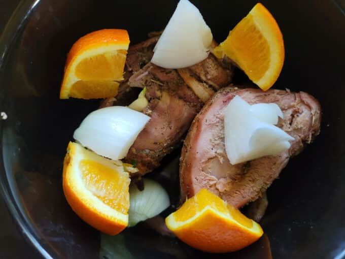 Onions, garlic and orange quarters in slow cooker.