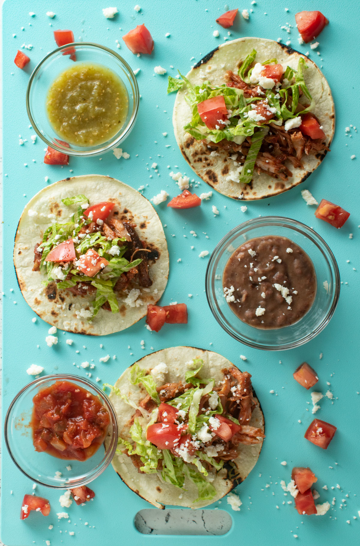 Rabbit tacos on an aqua colored board with sides.