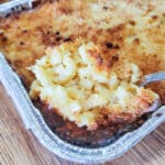 Spoon scooping out golden brown mac and cheese.