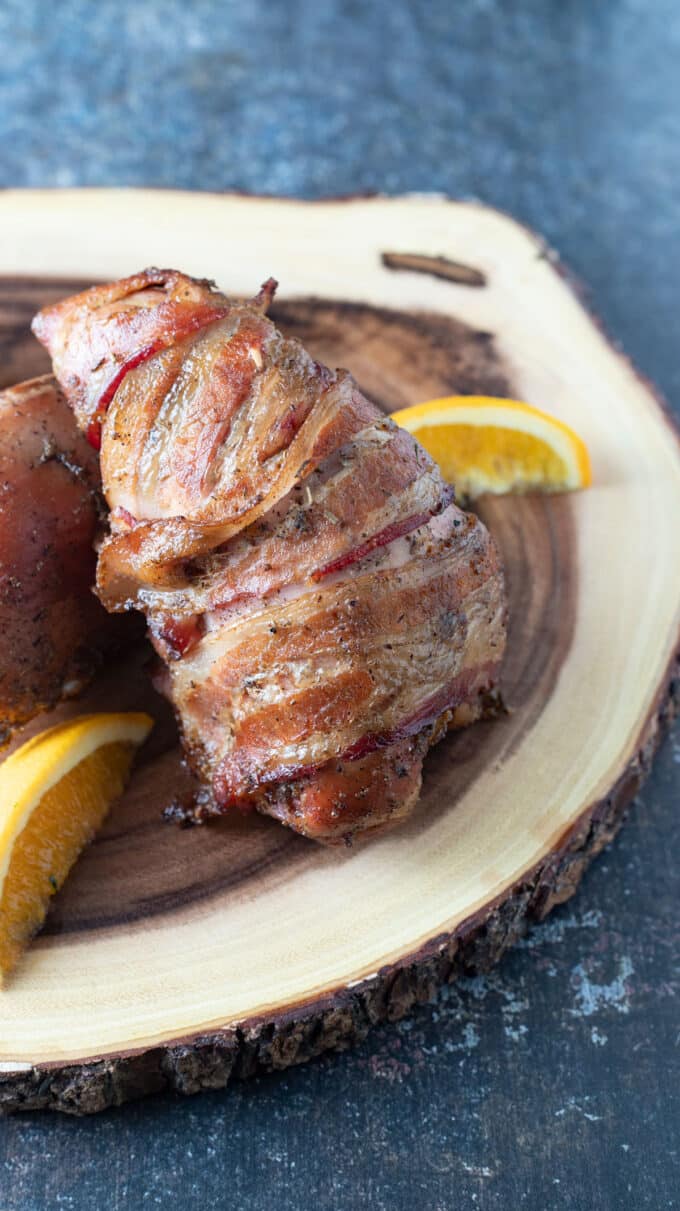 Bacon wrapped breast on wood slab.